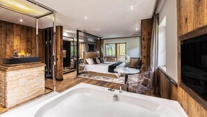 Une chambre moderne dotée d’un grand lit, d’une cheminée et d’un coin salon s éparé avec une table et des chaises.