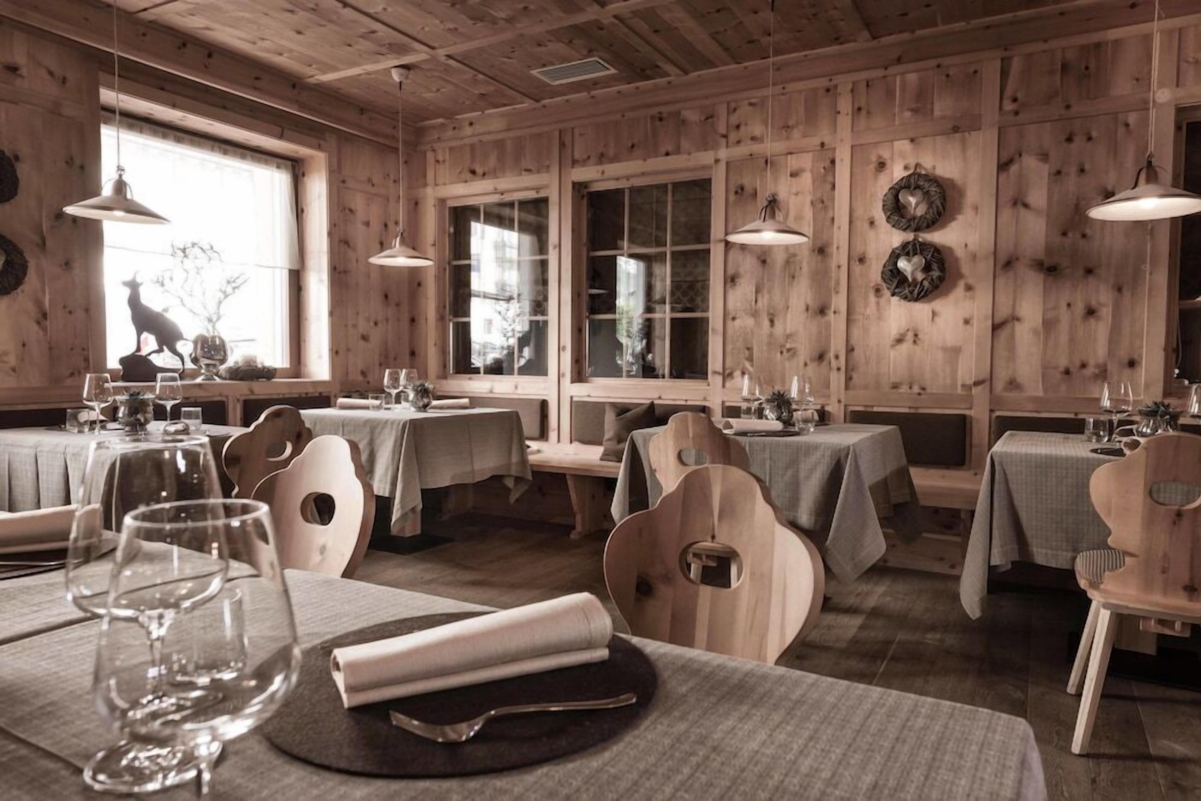 A restaurant with wooden paneled walls, multiple tables with chairs, and hanging pendant lights.