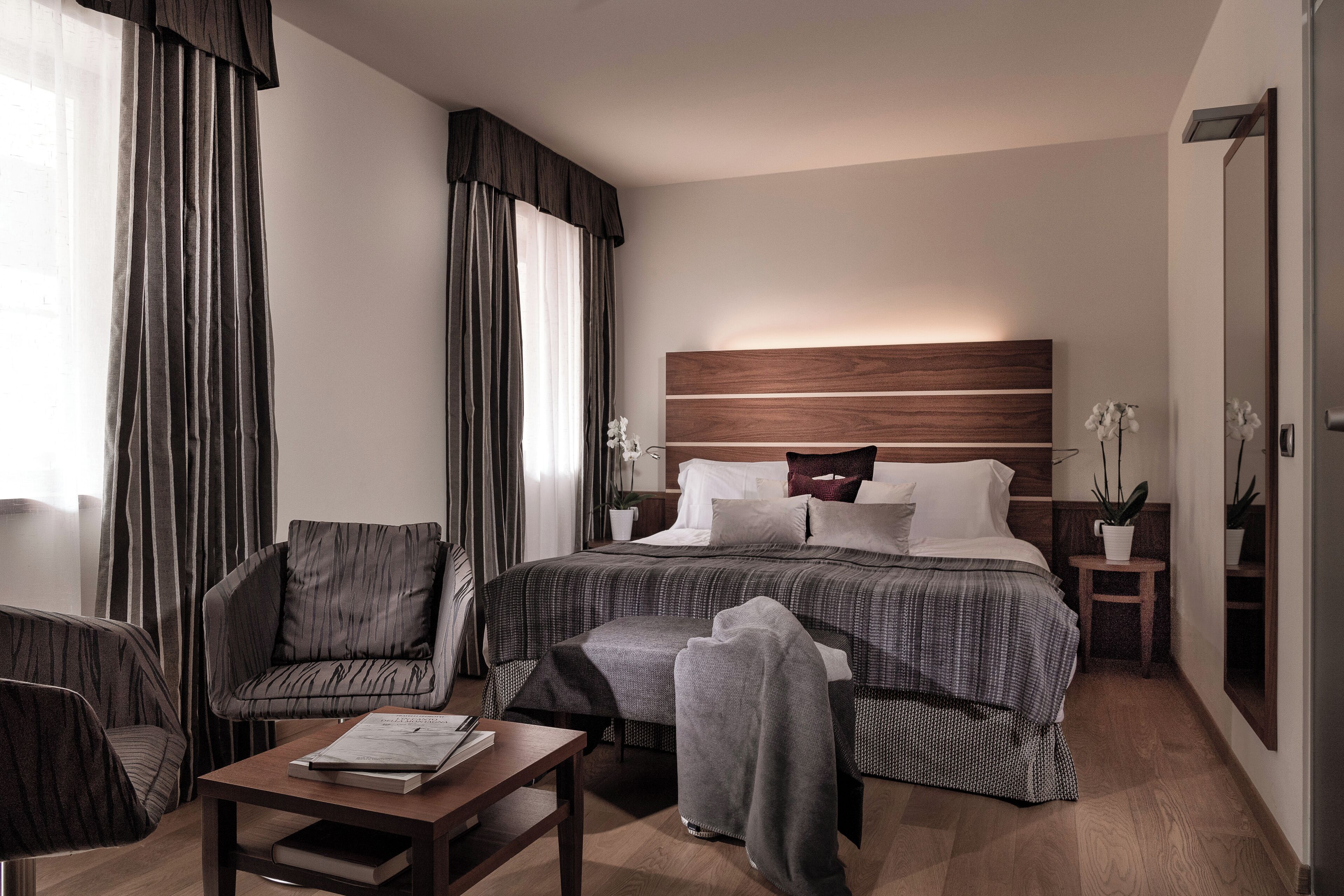 Une chambre d’hôtel avec un grand lit, une chaise, une petite table et une table de chevet avec une lampe.