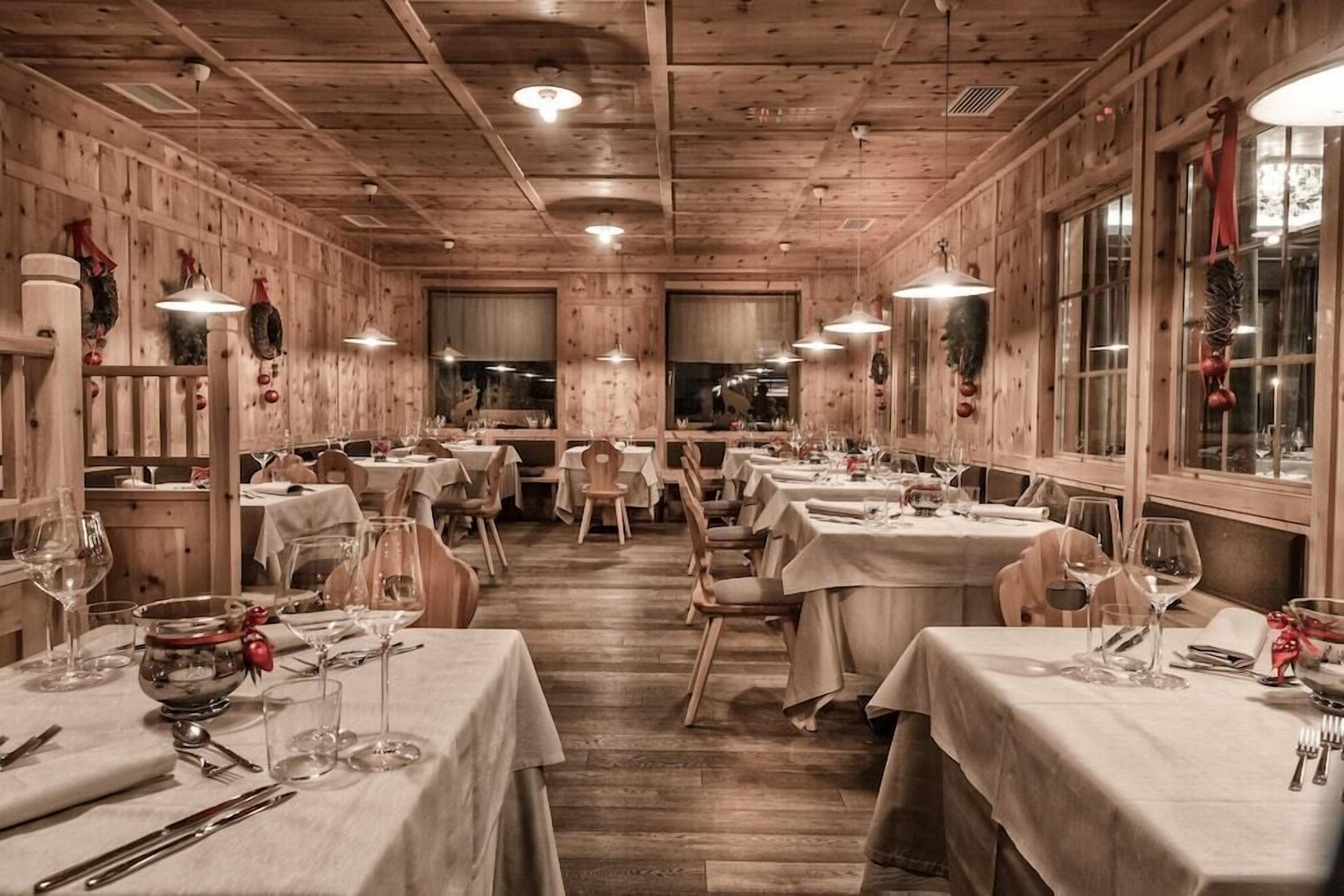 A cozy restaurant with wooden walls and ceiling, featuring multiple tables set for dining.