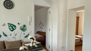 A modern living room with a wooden dining table, a vase with dried flowers, and a wall clock. - AI 7 NANI (Sedico)