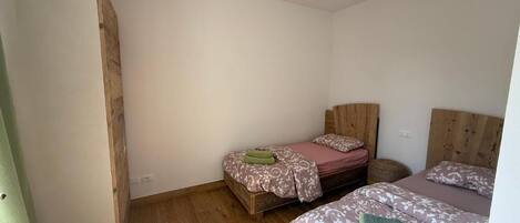 Een slaapkamer met twee bedden, houten vloeren en een kledingkast.