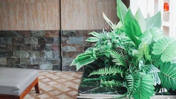 A room with a stone wall, a bed, a large air conditioning unit, and a planter with green plants.