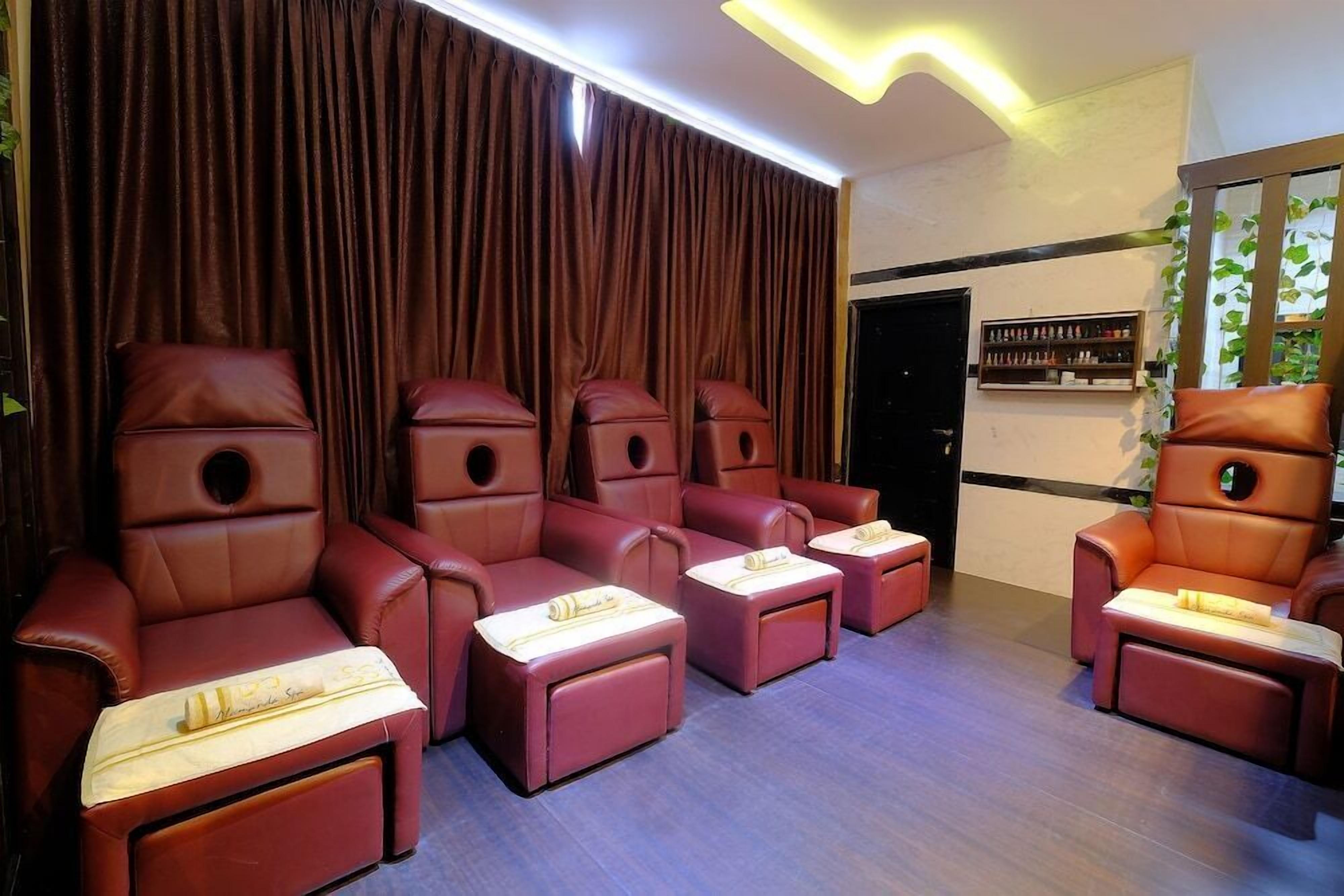 A massage room with multiple massage chairs and a small shelf with bottles.