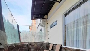 A covered outdoor area with stone walls and a tiled floor, featuring a window and a chair. - Batam Harbour Boutique Hotel And Spa (Batam)