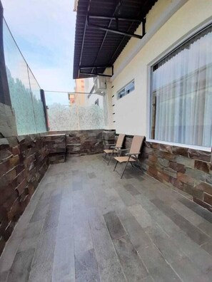 A covered outdoor area with stone walls and a tiled floor, featuring a window and a chair. - Batam Harbour Boutique Hotel And Spa (Batam)