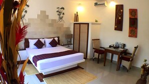 Une chambre d’hôtel équipée d’un lit, d’un bureau, d’une chaise, d’une armoire et d’un climatiseur fixé au mur.