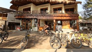 Un bâtiment à deux étages, doté d’un toit de chaume, d’un balcon et de vélos garés devant.