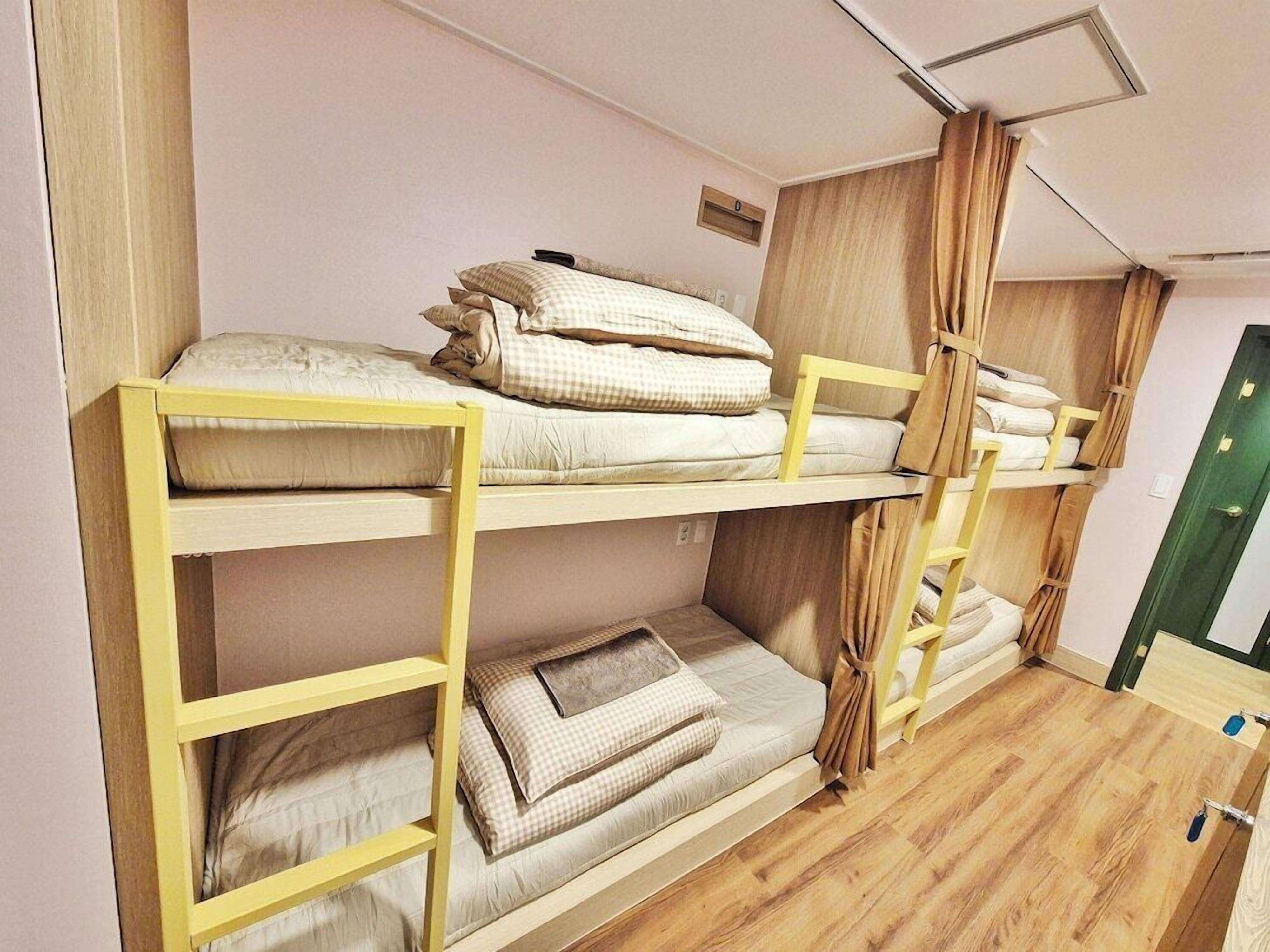 Une chambre avec un lit superposé, dont la structure est en bois et la literie est de couleur beige.