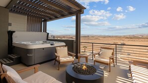 Un balcón con jacuzzi, sillones de descanso y una chimenea.