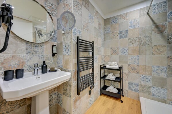 A bathroom with a sink, mirror, towel rack, and shelf with towels. - Music Hotel (Marseille)