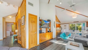 A spacious living area with a wooden staircase, a television, and a dining area with a view.