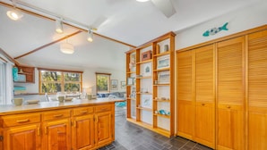 A kitchen with wooden cabinets, a central island, and a built-in shelving unit with various items.