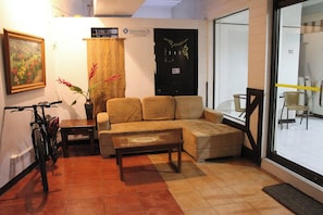 Uma sala de estar com um sofá, uma mesa de centro, uma bicicleta e uma porta com uma placa.