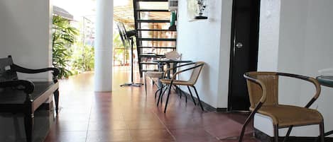 A spacious room with a bed, a dining area with chairs and a table, and a view of the outside.