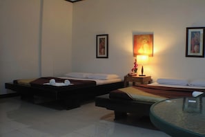 Quarto de hotel com duas camas, uma mesa pequena, um abajur e obras de arte nas paredes.