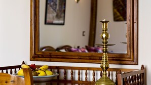 A wooden-framed mirror reflecting a room with a fruit bowl, a candle, and a wall-mounted light fixture. - Villa Quietta (Essaouira)