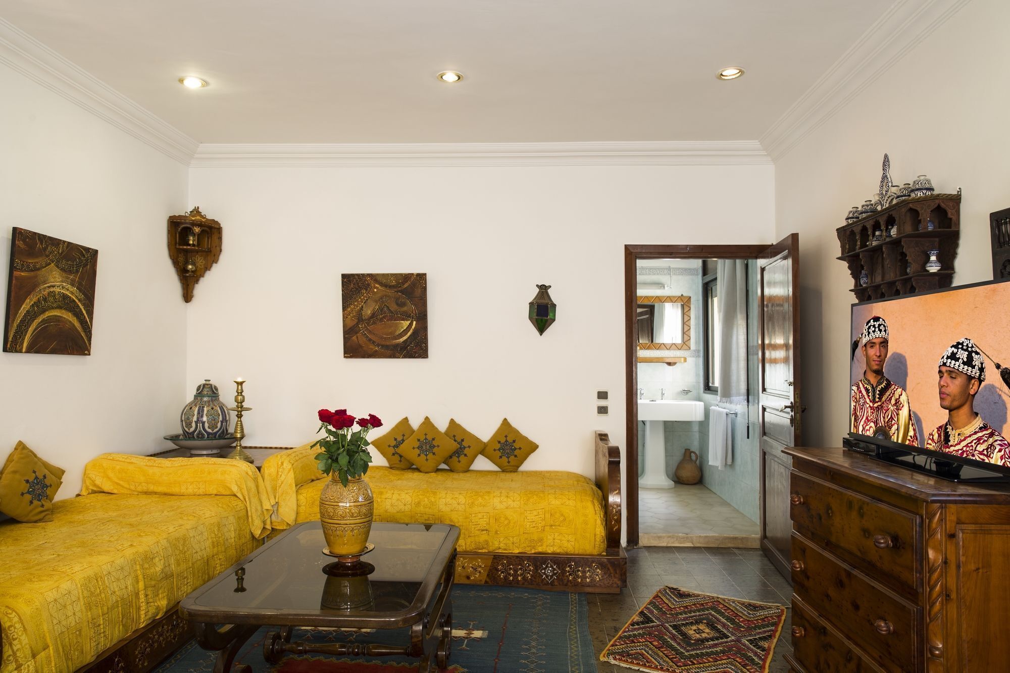 A living room with a sofa set, a coffee table, a vase with flowers, and a television.