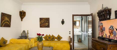 A living room with a sofa set, a coffee table, a vase with flowers, and a television.