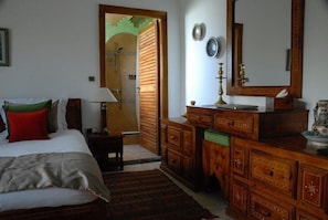 Ein Schlafzimmer mit Bett, Kommode, Spiegel und einer Tür zum Badezimmer.