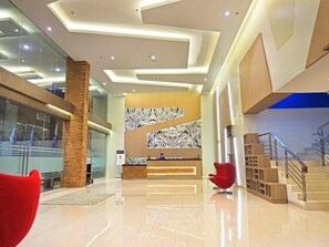 Un vestíbulo moderno con una recepción, una escalera y una silla roja.