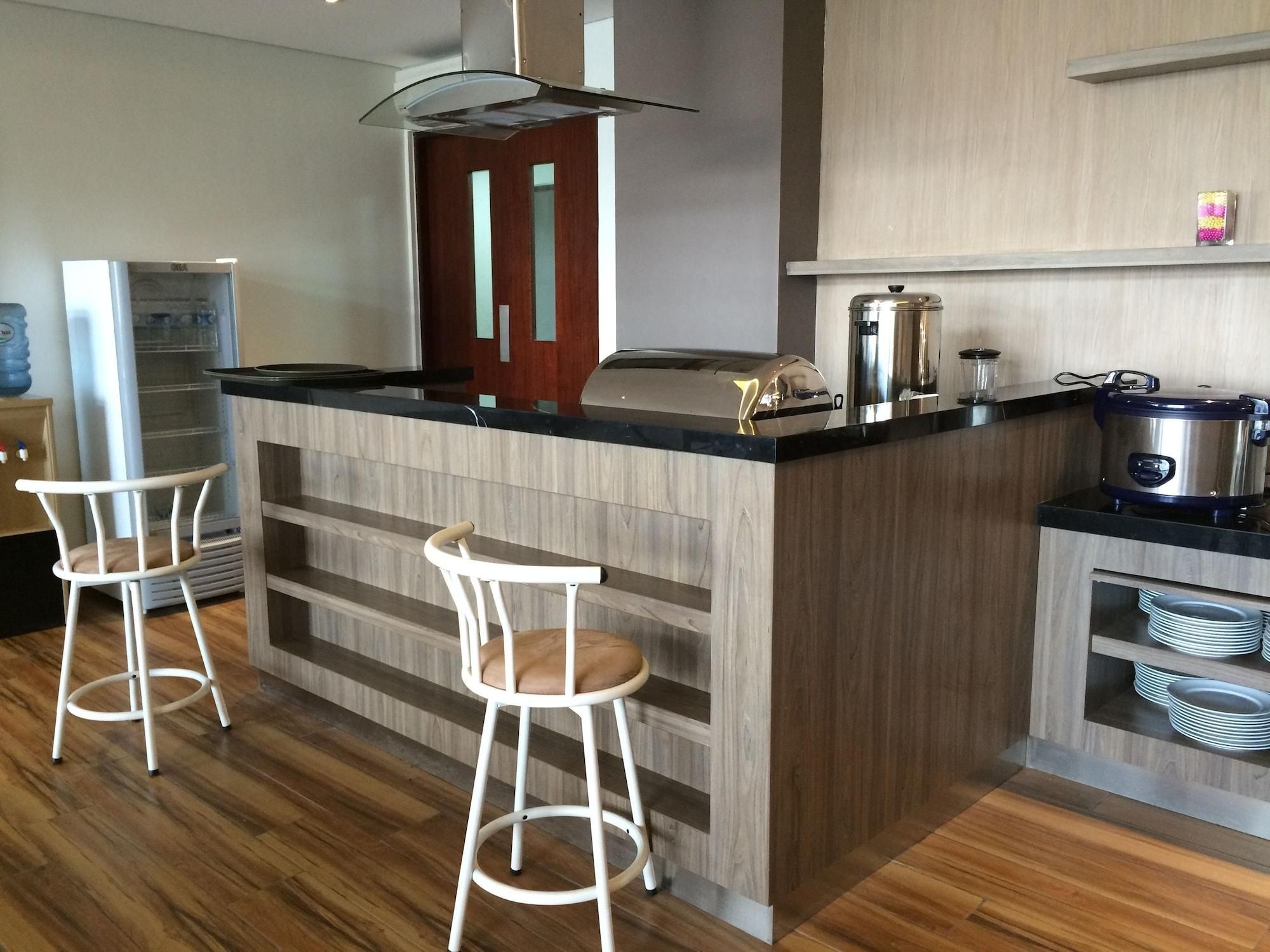 Een moderne keuken met een centraal eiland, barstoelen, een koelkast, een fornuis en een spoelbak.