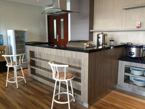 Een moderne keuken met een centraal eiland, barstoelen, een koelkast, een fornuis en een spoelbak.