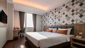 Habitación de hotel con cama, escritorio, silla, televisor y pared con diseño.