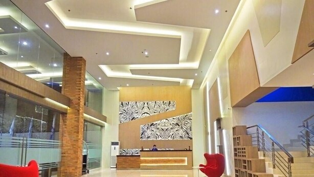 A modern lobby with a reception desk, a staircase, and a red chair. - Hotel 88 Fatmawati (Jakarta)