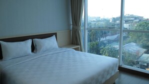 A hotel room with a large bed, a view of the city through a large window, and a curtain on the window. - Hotel 88 Fatmawati (Jakarta)