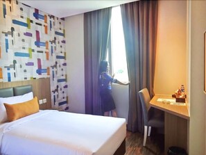 A hotel room with a bed, a desk, and a window with curtains. - Hotel 88 Fatmawati (Jakarta)
