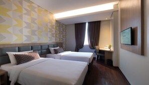 A hotel room with two beds, a desk, a chair, a TV, and a window with curtains. - Hotel 88 Fatmawati (Jakarta)