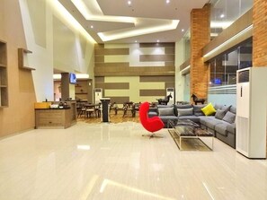 Un interior moderno con comedor, un conjunto de sofás, una silla roja y una zona de cocina.
