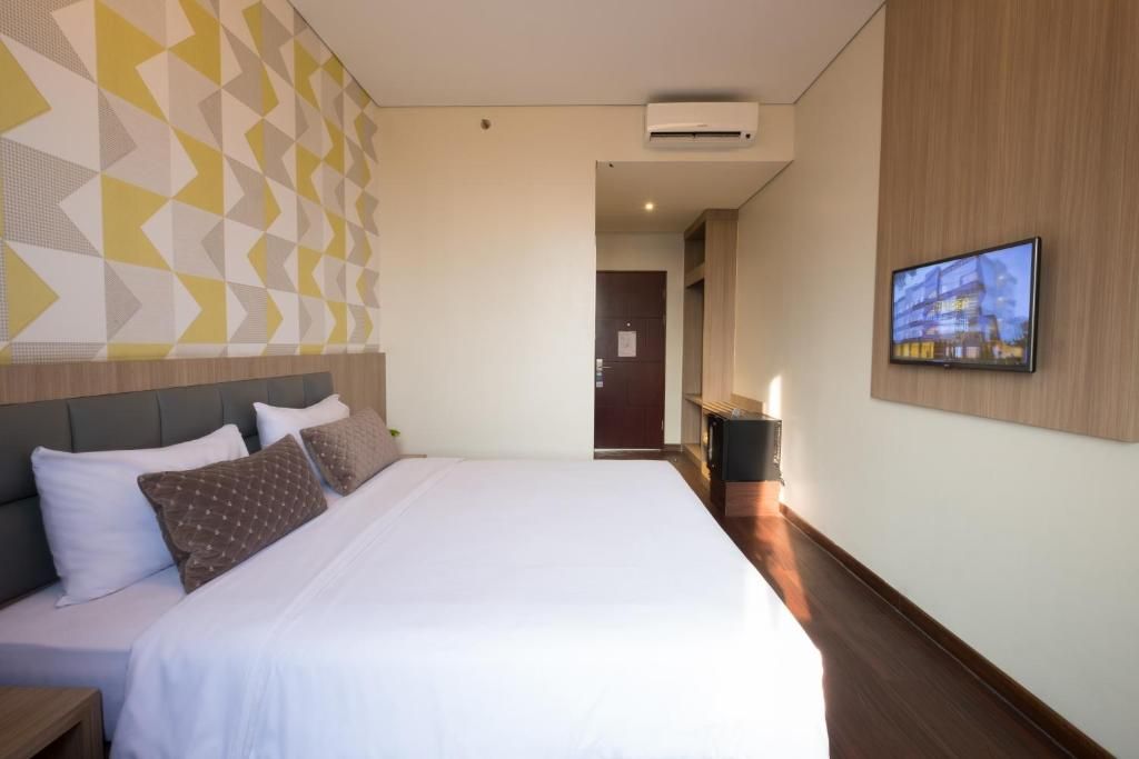 Een hotelkamer met een bed, een televisie en een wandairconditioner.