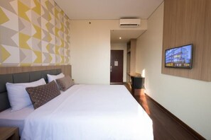 Una habitación de hotel con cama, televisión y aire acondicionado instalado en la pared.