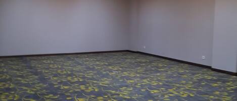 A room with a dark floor, light-colored walls, and a ceiling with recessed lighting.