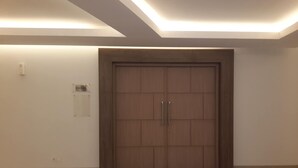 A large wooden door with two handles, a light switch, and a small sign on the wall to the left. - Hotel 88 Fatmawati (Jakarta)