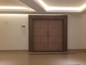 A large wooden door with two handles, a light switch, and a small sign on the wall to the left. - Hotel 88 Fatmawati (Jakarta)