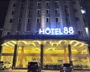 Een hotel met een opvallend bord waarop 'HOTEL 88' staat en een moderne ingang met een overdekt gebied.