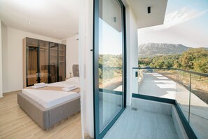 A bedroom with a bed, a wardrobe, and a balcony with a mountain view.