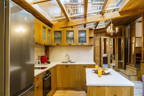 Eine moderne Küche mit Holzschränken, einem Edelstahlkühlschrank, einer Spüle und einer Frühstückstheke mit Orangensaft.