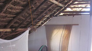 Een kamer met een bed, een ventilator en een raam met gordijnen.
