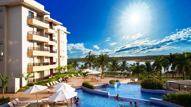A hotel with a pool, outdoor seating, and a view of the sea. - Marina Flat And Nautica (Caldas Novas)