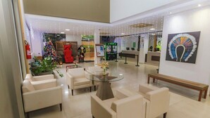 A lobby with a glass coffee table surrounded by sofas, a reception desk, and a Christmas tree. - Marina Flat And Nautica (Caldas Novas)