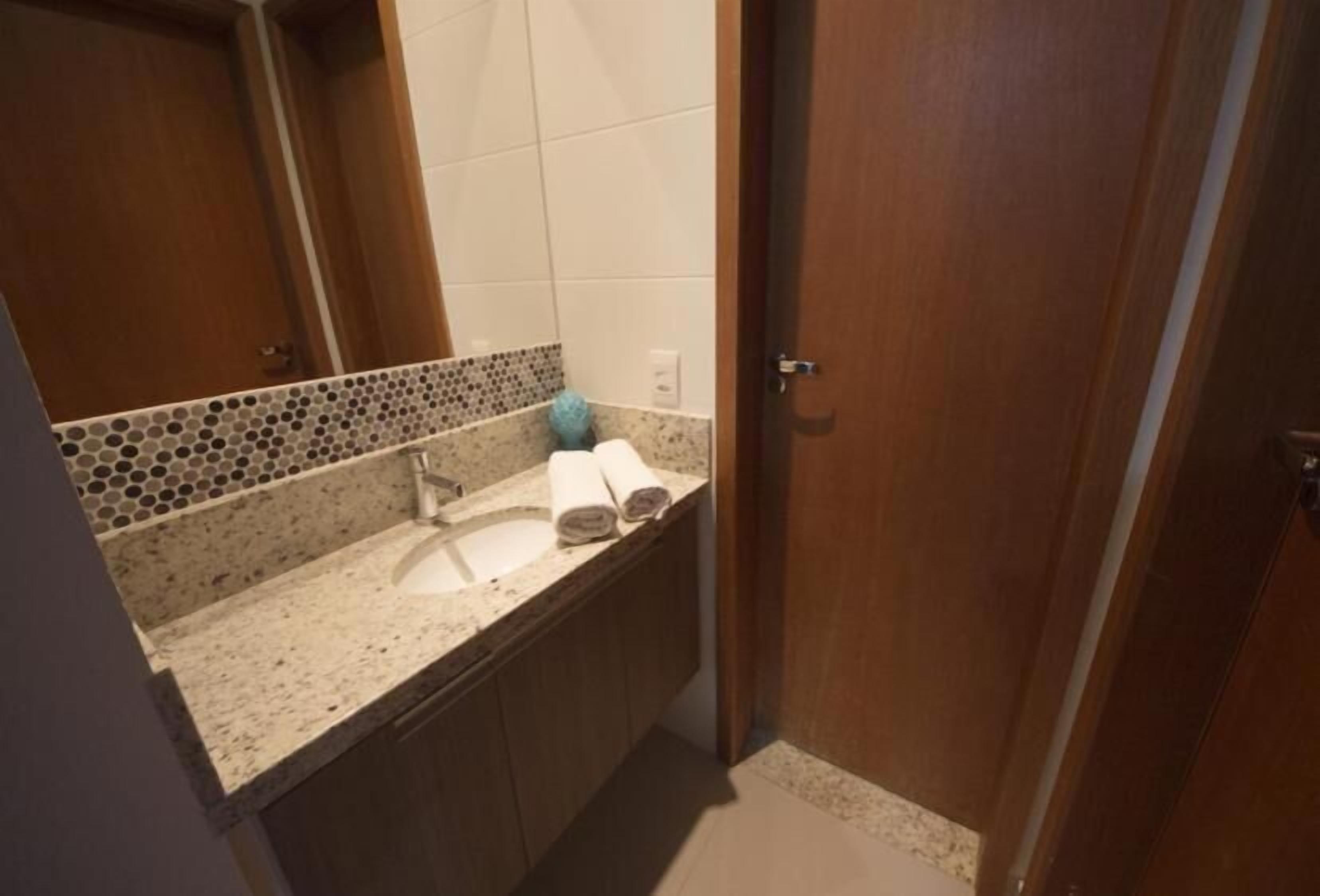 Un baño con lavamanos, espejo y armarios de madera.