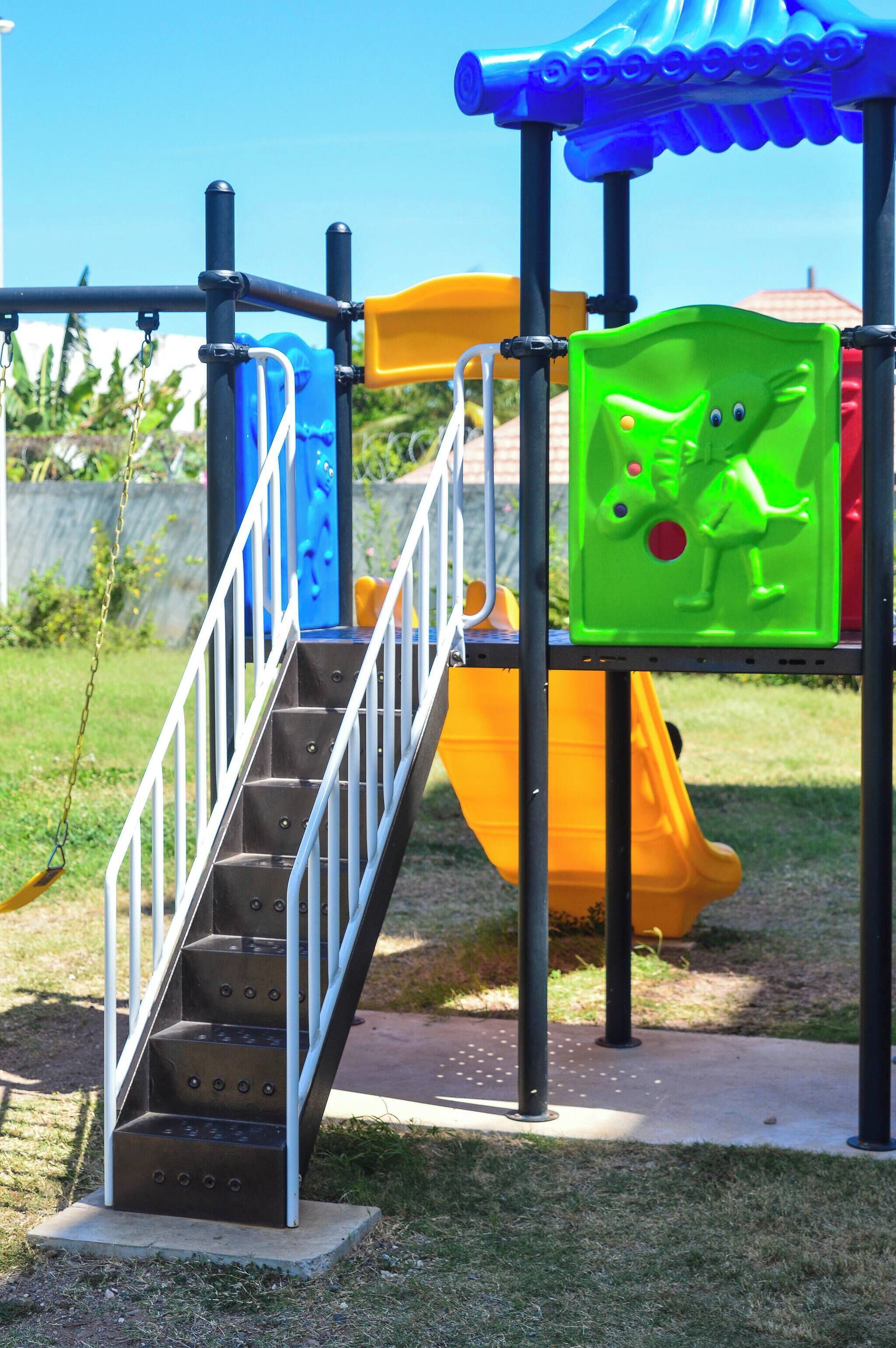 A playground with a metal staircase, a yellow slide, and a blue climbing structure.