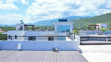 Una terraza en la azotea con vistas a un paisaje urbano y montañas.