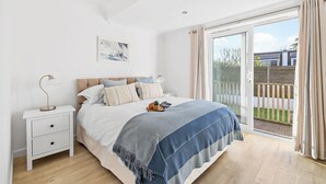 Una camera da letto con un letto, un comodino, una lampada e una porta scorrevole in vetro su un balcone.