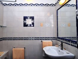 Un baño con dos lavamanos, un espejo y azulejos decorativos.