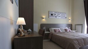 A hotel room with a bed, a desk, a chair, a lamp, and a wall sign with room amenities. - Suite 39 BnB (Salerno)